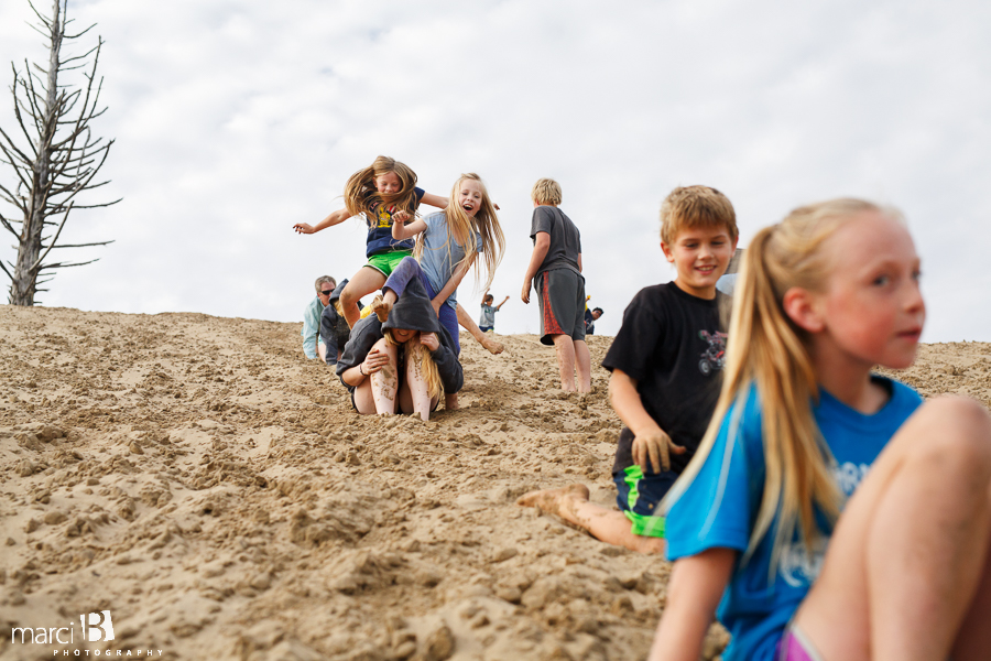 Playing on the dunes - Family photographer - Oregon Coast - leapfrog down a sand dune