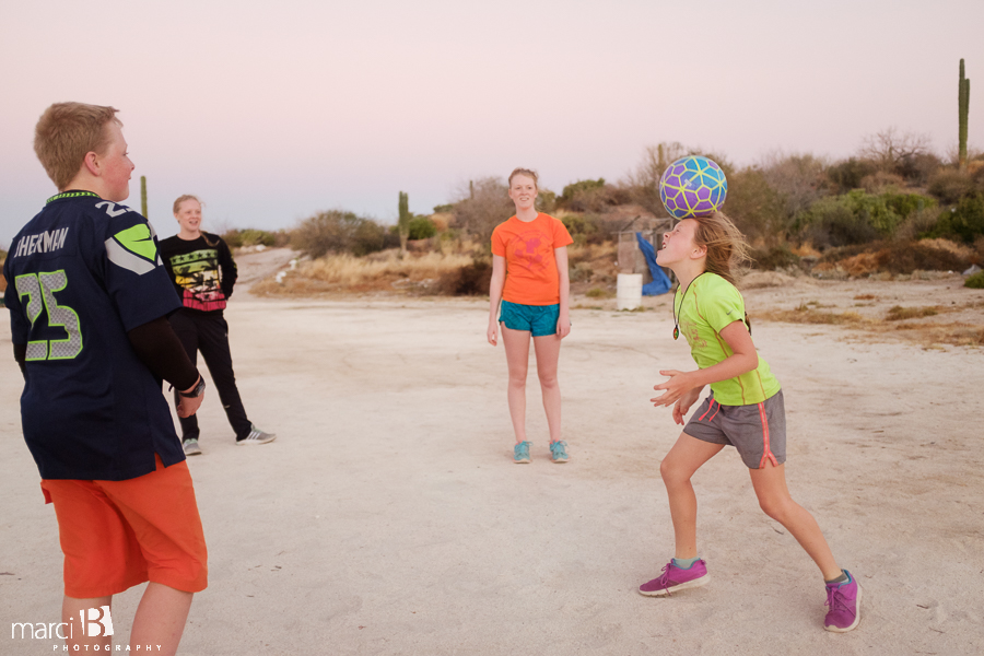 girl heading the ball - playing soccer while camping - Baja family road trip