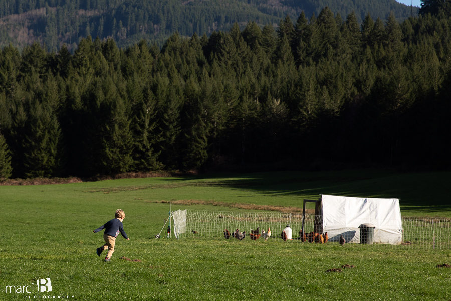 oregon farm boy runs to the chicken coop with mountain in background