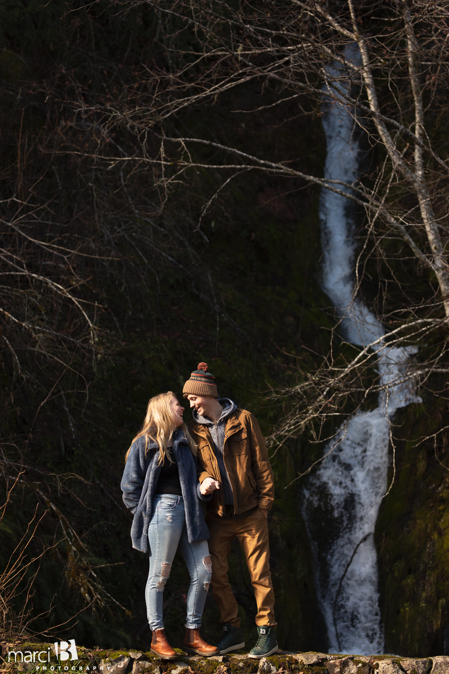 oregon engaged couple standing in front of waterfalls
