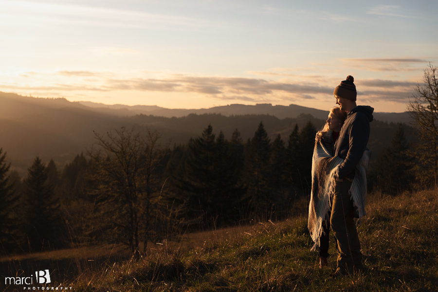 pacific northwest engaged couple hugging while looking at sunset