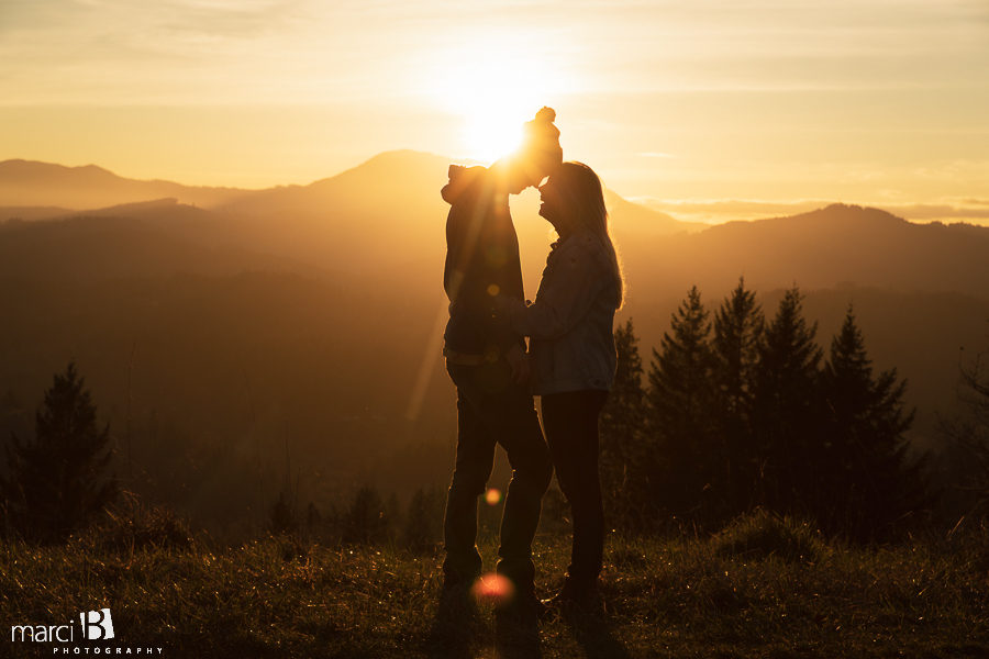 sunflare and silhouette of engaged couple with sunset in the background
