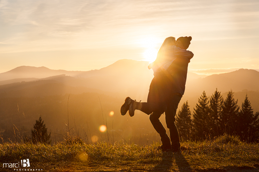 man swinging fiance with sunset in background and lens flare