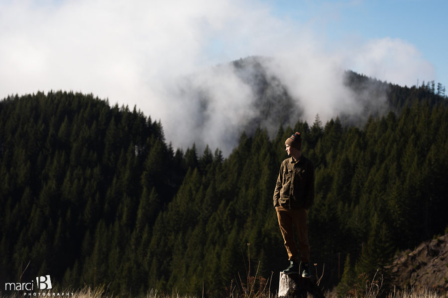 iconic pacific northwest man standing on stump with forest and clouds in background