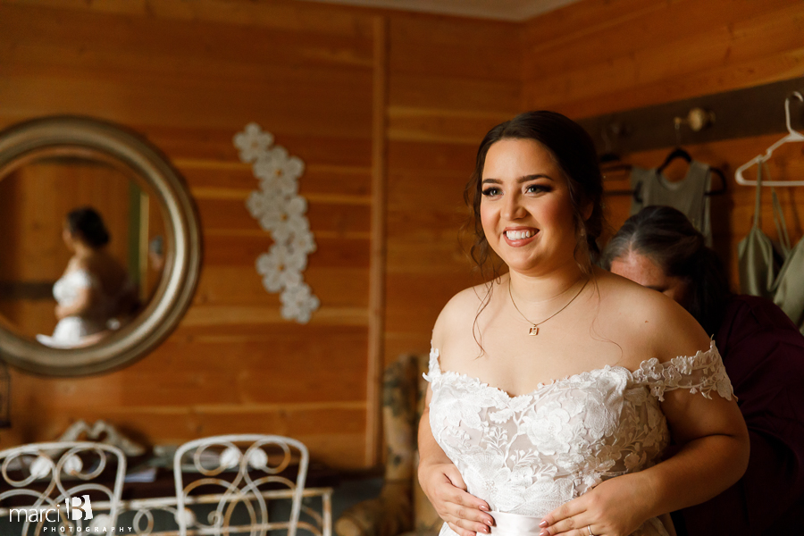 Mother of the bride helping daughter with gown